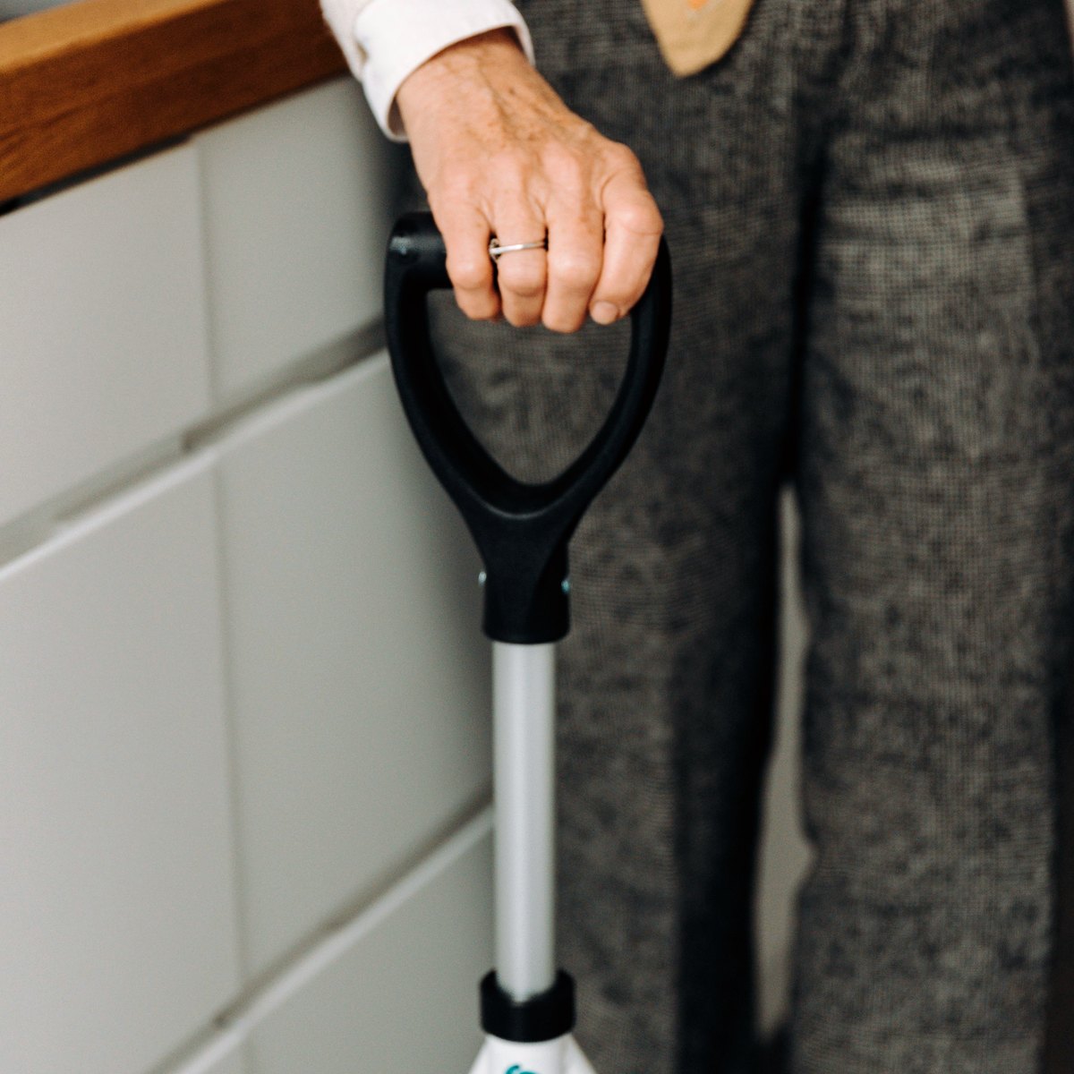 Older person using a walking aid in a home kitchen