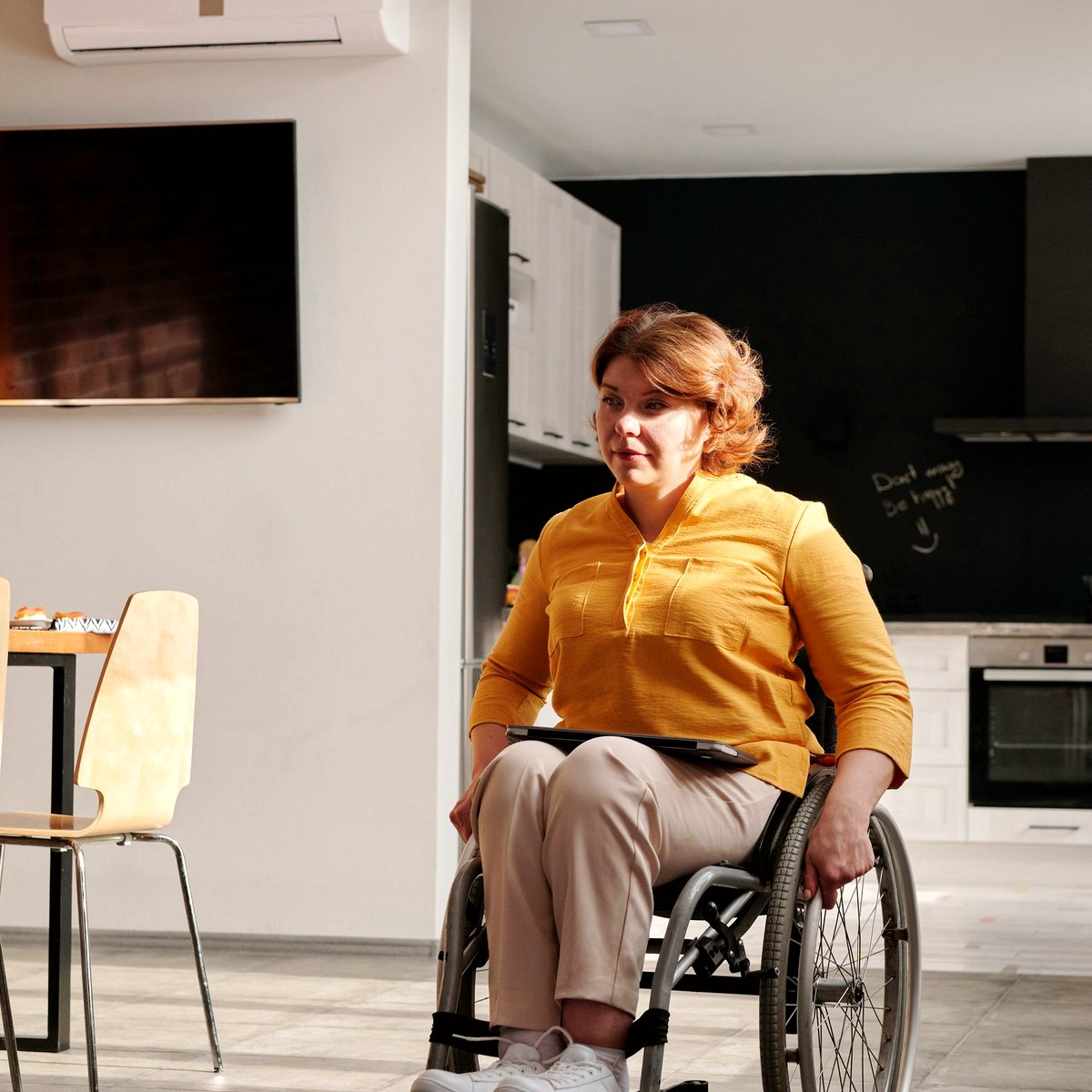 Adult using a wheelchair in a home kitchen and living space
